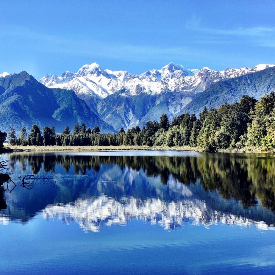 The snow capped mountain range perfectly reflected in Lake Matheson in New Zealand