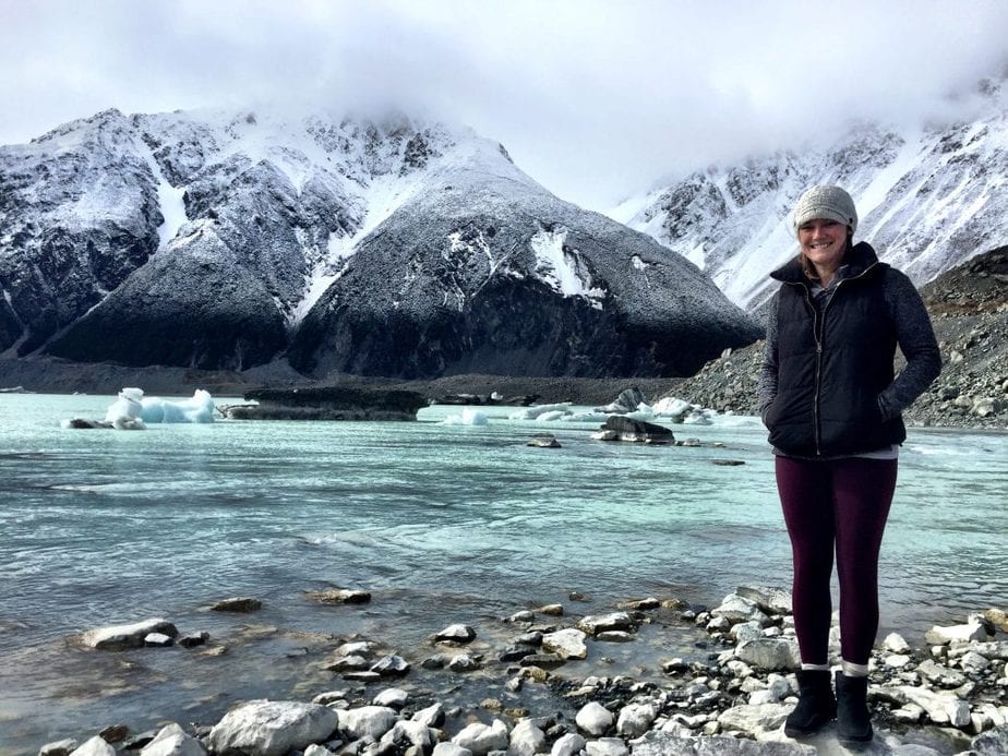 Me standing in front a lake with floating glaciers and snowy mountains in the background