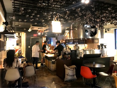Inside Coffee Lab with portafilters hanging from the ceiling as decoration, customers enjoying coffee and the baristas helping a customer. 